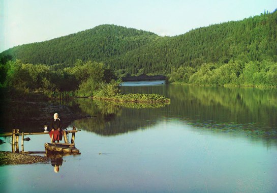 A woman is seated in a calm spot on the Sim River, part of the Volga watershed in 1910